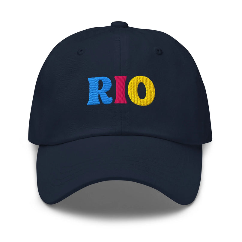 Casquette bleu marine avec le texte 'RIO' brodé en lettres colorées bleu, rouge et jaune, évoquant l'énergie, les couleurs des carnavals brésiliens et l'ambiance festive de Rio de Janeiro. Accessoire authentique inspiré de la culture brésilienne.