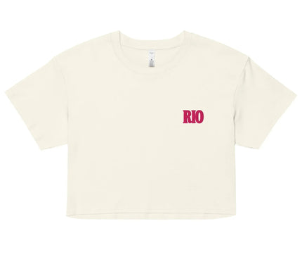 Crop top blanc avec le mot 'Rio' écrit en rose sur le côté gauche de la poitrine, inspiré de la culture brésilienne et du style vibrant de Rio de Janeiro. Style décontracté parfait pour l'été, idéal pour refléter une ambiance festive et ensoleillée.