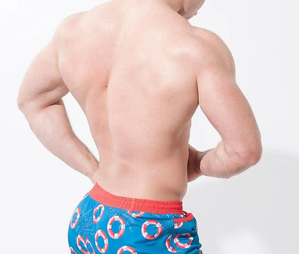 Short de bain homme inspiré des plages brésiliennes, motif bouées de sauvetage rouge et blanc sur fond bleu, ceinture rouge pour un style tropical et décontracté, parfait pour les journées ensoleillées et les vacances.