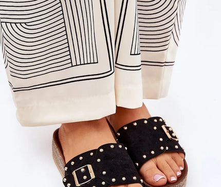 Sandales noires à décorations métalliques dorées avec boucle, inspirées de l'artisanat brésilien, portées avec une tenue légère et élégante. Idéales pour un style estival chic mêlant simplicité et raffinement, évoquant le charme festif et tropical du Brésil.