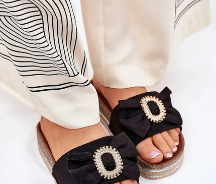 Sandales noires d'inspiration brésilienne ornées d'une boucle décorative brillante, présentées avec une tenue chic et fluide. Parfaites pour un style bohème élégant, ces sandales en matériaux artisanaux et confortables reflètent l'esprit tropical et festif du Brésil, idéales pour compléter une tenue estivale.