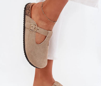 Sandales élégantes pour femmes en suédine écologique beige, avec semelle en liège profilée et boucle réglable. Design moderne avec bouts couverts, parfait pour un usage quotidien. Chaussures confortables et stylées portées avec un pantalon blanc.