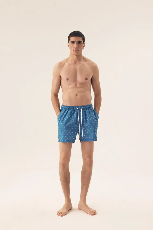 Homme portant un maillot de bain bleu inspiré des plages brésiliennes, avec des motifs marins subtils, reflétant le style tropical moderne et décontracté. Idéal pour les journées en bord de mer ou une promenade sur les plages ensoleillées.