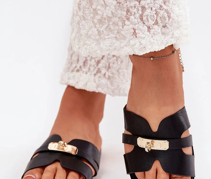 Sandales noires élégantes à design minimaliste avec détails dorés, inspirées du style brésilien et idéales pour un look côtier. Portées avec un pantalon de dentelle blanche, elles illustrent un équilibre entre sophistication et confort, parfaites pour flâner sur les plages ou dans les rues vibrantes de Rio.