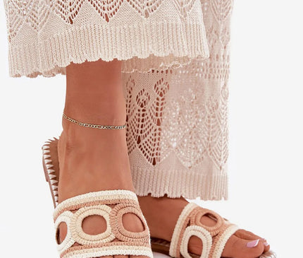 Sandales inspirées de l'artisanat brésilien avec détails tissés, design élégant et bohème, parfaites pour l'été et associées à une robe crochetée ajourée blanche, évoquant les plages de Bahia et l'esprit décontracté du Brésil.