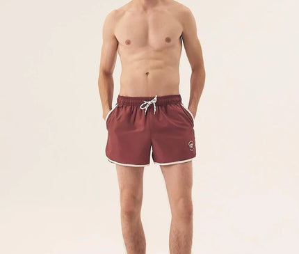 Short de bain homme couleur bordeaux, inspiré de l'énergie vibrante du littoral brésilien, avec bordures blanches, cordon ajustable et coupe courte évoquant l'élégance tropicale et le dynamisme brésilien. Parfait pour la plage, le sport ou des moments de détente en été.