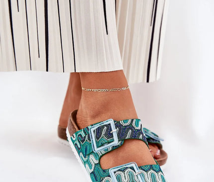 Sandales artisanales inspirées du Brésil avec des motifs vibrants verts et bleus, boucles décoratives, semelle confortable en liège et design reflétant l’élégance décontractée des traditions brésiliennes.