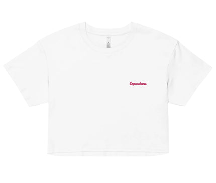 Crop top blanc minimaliste avec inscription rouge Copacabana, inspiré par le style de vie brésilien et la plage emblématique de Rio de Janeiro. Design élégant et décontracté évoquant l'esprit chaleureux et festif du Brésil.