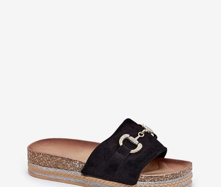 Claquette en suédine écologique noire avec détail doré à l'avant, montée sur une plateforme de 3,5 cm décorée de paillettes et liège. Semelle profilée et design glamour, idéale pour l'été.