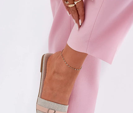 Sandales plates pour femmes en tissu textile beige, avec une fine bride ornée d'une boucle métallique à l'avant, associées à un pantalon rose clair. Élégantes et confortables, idéales pour l'été, avec une semelle de 1 cm en cuir écologique et tissu.