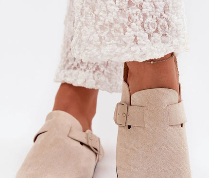 Claquettes pour femmes avec semelle en liège et en suédine écologique beige. Design avec bouts fermés, boucle ajustable pour un maintien parfait, et semelle profilée de 2,5 cm offrant confort toute la journée. Parfaites pour un style quotidien élégant et confortable.
