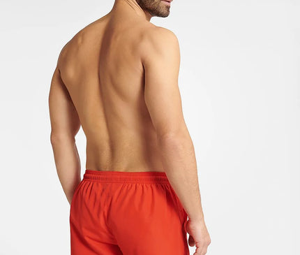Homme portant un short de bain rouge énergique GUILD à séchage rapide, coupe ample avec taille élastique ajustable, idéal pour la plage et les activités aquatiques.