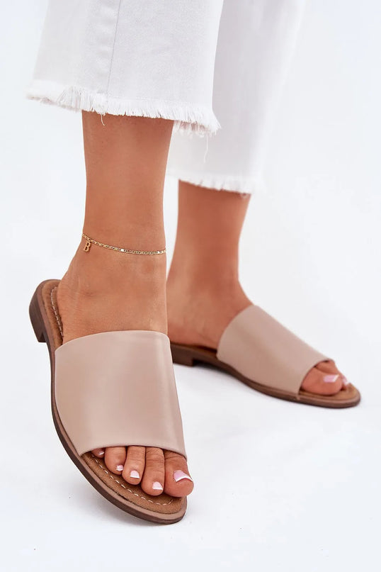 Sandales minimalistes brésiliennes en cuir beige, design épuré et ouvert, adaptées pour un confort estival. Associées à une tenue décontractée et élégante, idéales pour les balades en bord de mer ou en ville.