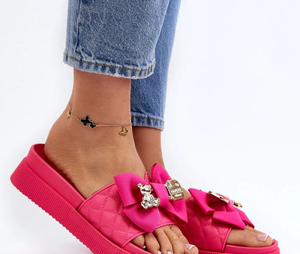 Claquettes pour femmes en simili cuir rose avec plateforme massive de 4,5 cm, ornées d'un nœud en tissu rose et d'un fermoir décoratif avec un ours en peluche argenté et une plaque dorée. Chaussures élégantes et tendance, parfaites pour la saison estivale.