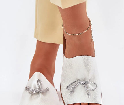 Sandales blanches élégantes avec un nœud subtil en corde argentée, inspirées du style décontracté brésilien. Idéales pour une tenue urbaine ou pour une promenade en bord de mer, symbolisant un mélange de raffinement et de simplicité tropicale.
