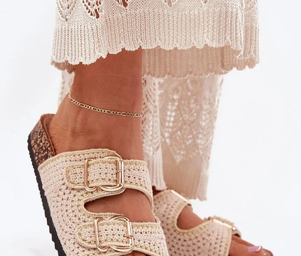 Sandales tissées style bohème rappelant les traditions artisanales brésiliennes, en crochet beige avec boucles dorées, semelles en liège, accompagnées d'une tenue légère en dentelle. Idéal pour un look moderne et décontracté inspiré des plages du Brésil.