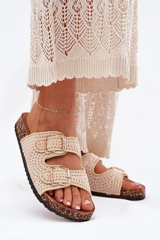 Sandales tissées style bohème rappelant les traditions artisanales brésiliennes, en crochet beige avec boucles dorées, semelles en liège, accompagnées d'une tenue légère en dentelle. Idéal pour un look moderne et décontracté inspiré des plages du Brésil.
