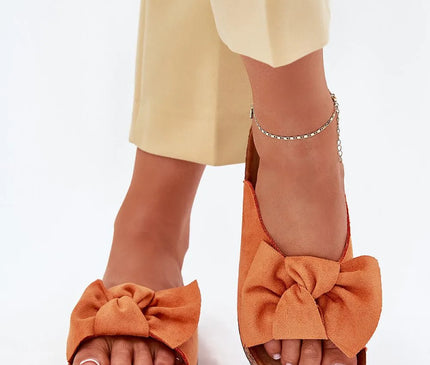 Sandales élégantes et décontractées en suédine orange avec un nœud volumineux évoquant l'artisanat brésilien, posées sur une semelle en liège confortable, idéale pour un style estival inspiré des plages tropicales.