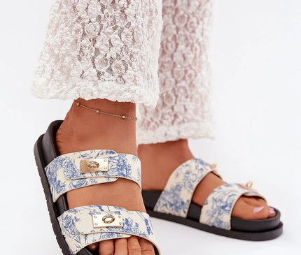 Sandales d'inspiration brésilienne, avec des motifs tropicaux bleus sur fond beige, deux brides ajustables avec détails dorés, semelle noire confortable, idéales pour un style chic et décontracté en été.