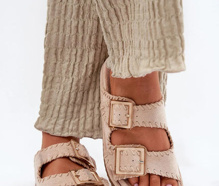 Claquettes pour femmes en suédine écologique, couleur beige, avec coutures décoratives et boucles imposantes sur le dessus. Semelle profilée adaptée à la forme du pied pour un confort optimal. Idéales pour les tenues estivales, urbaines ou les voyages de vacances.