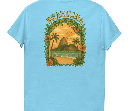 T-shirt bleu clair avec un motif tropical inspiré du Brésil, représentant un coucher de soleil, des palmiers, des montagnes, une plage et le mot 'Brazilina' en lettres jaunes. Design encadré par des feuilles et des fleurs exotiques, symbolisant l'énergie et la richesse culturelle brésiliennes.