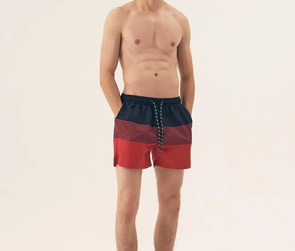 Homme portant un short de bain rouge et noir avec cordons de serrage, à imprimé tendance, fabriqué en polyester léger et à séchage rapide, idéal pour la plage ou la piscine.