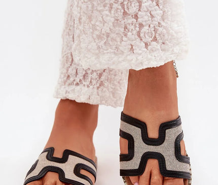 Mules femme en cuir écologique et matériau textile, ornées d'une décoration dorée sur la semelle, avec un design géométrique noir contrastant sur fond beige, montées sur un talon plat de 1,5 cm, parfaites pour les tenues décontractées et estivales.