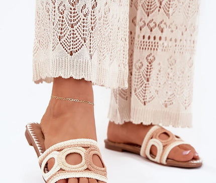 Sandales d'inspiration brésilienne avec détails tissés, design bohème et élégant, parfaites pour l'été. Chaussures ouvertes évoquant l'artisanat traditionnel et les plages de Bahia ou Rio, portées avec une tenue en dentelle beige.