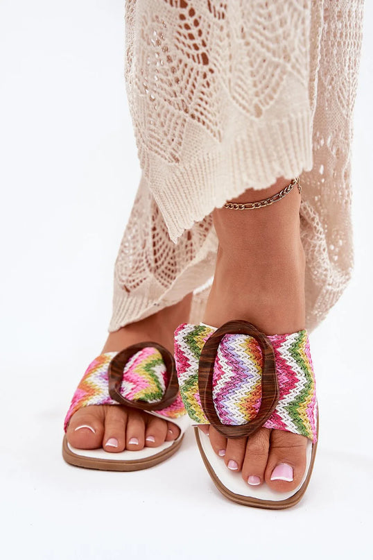 Sandales artisanales brésiliennes colorées pour femme avec motif tissé à chevrons multicolores, boucle en bois décorative, portées avec une robe en crochet beige – chaussures inspirées du style de vie décontracté et tropical du Brésil, parfaites pour un look plage ou urbain.