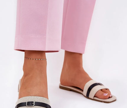 Claquettes plates pour femmes en tissu textile, ornées d'une fine bride avec boucle noire à l'avant. Semelle basse de 1 cm en cuir écologique et tissu, parfaites pour les journées chaudes, portées avec un pantalon rose élégant.