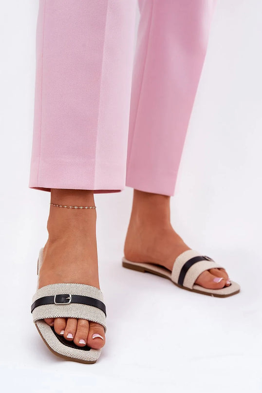 Claquettes plates pour femmes en tissu textile, ornées d'une fine bride avec boucle noire à l'avant. Semelle basse de 1 cm en cuir écologique et tissu, parfaites pour les journées chaudes, portées avec un pantalon rose élégant.