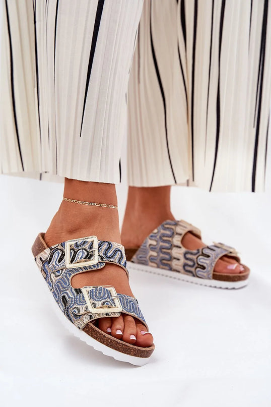 Sandales élégantes inspirées des traditions artisanales brésiliennes avec motifs tissés rappelant le tissage ancestral, dotées de boucles dorées. Elles incarnent l'esprit des plages tropicales et offrent un style exotique et confortable.