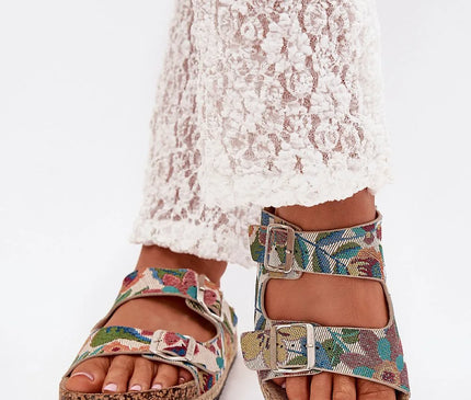 Sandales pour femmes de la marque Lee Cooper avec une plateforme en liège tressé de 2,5 cm, dotées de deux brides réglables avec boucles métalliques, motif coloré floral sur tissu, semelle en cuir suédé écologique, portées avec un pantalon en dentelle blanche, parfaites pour les journées d'été.