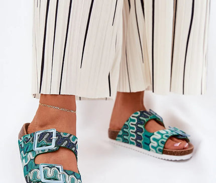 Sandales inspirées du Brésil, avec des motifs ondulés multicolores bleu et vert, dotées de deux boucles ajustables et d'une semelle en liège confortable. Ces sandales incarnent l'esprit brésilien avec leur style artisanal et élégant, parfait pour un look décontracté et raffiné.