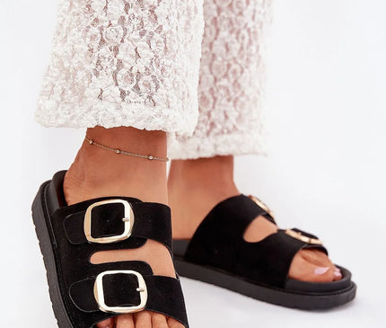 Sandales noires avec larges brides en suédine et boucles dorées, inspirées du style décontracté et élégant du Brésil. Idéales pour le confort quotidien et une allure chic, elles évoquent l'esprit des plages de Rio et des ruelles de Bahia.