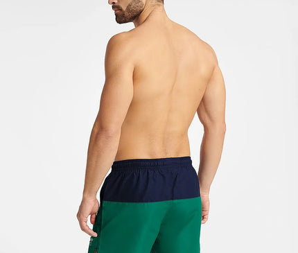 Homme de dos portant un maillot de bain GEM bicolore vert et bleu marine, taille mi-cuisse avec taille élastiquée et cordon de serrage, idéal pour les sports nautiques et l'été, avec petite ouverture sur les côtés pour une meilleure liberté de mouvement.