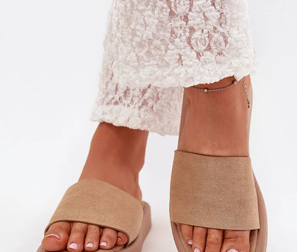 Sandales minimalistes beige pour femmes, inspirées du style décontracté et tropical du Brésil, avec une large sangle en matière légère et confortable, idéales pour les journées estivales ou une tenue chic et décontractée. Portées avec un pantalon en dentelle blanche.