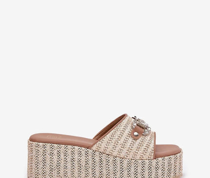 Sandales à plateforme tressées d'inspiration brésilienne, avec semelle épaisse et détails en métal, évoquant un style bohème et estival, parfaites pour un look décontracté et sophistiqué.