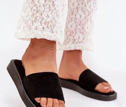 Sandales noires minimalistes et élégantes inspirées par le style estival brésilien, portées avec un pantalon en dentelle blanc. Idéales pour les promenades en bord de mer ou les soirées tropicales, ces sandales incarnent la simplicité et le confort des tenues décontractées brésiliennes.