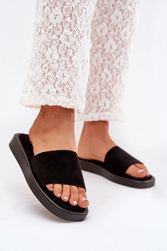 Sandales noires minimalistes et élégantes inspirées par le style estival brésilien, portées avec un pantalon en dentelle blanc. Idéales pour les promenades en bord de mer ou les soirées tropicales, ces sandales incarnent la simplicité et le confort des tenues décontractées brésiliennes.