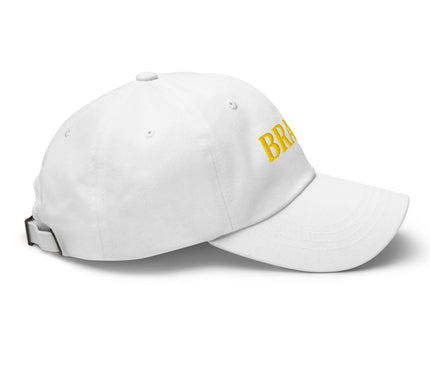 Casquette blanche style décontracté, motif 'Brazil' brodé en jaune sur le devant, inspirée de la culture brésilienne, les traditions festives et l'ambiance ensoleillée des grandes villes comme Rio de Janeiro et São Paulo.