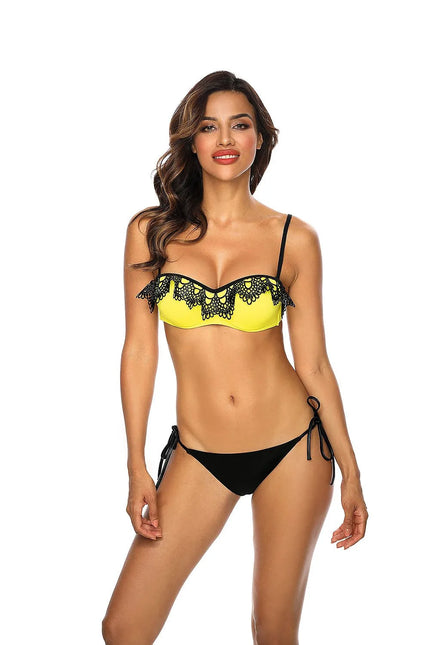 Bikini Malaga élégant et sexy avec soutien-gorge bardot jaune décoré de dentelle guipure noire, bonnets à armatures push-up, bretelles réglables et culotte noire nouée sur les hanches, idéal pour l'été.