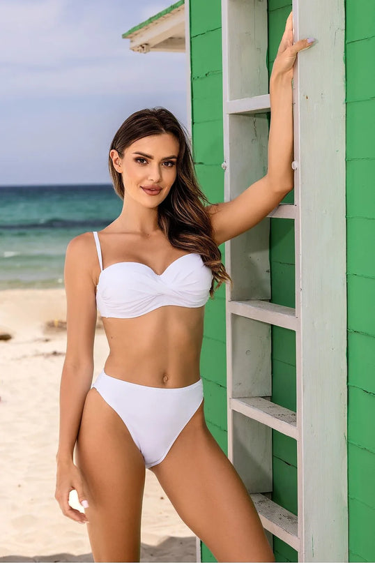 Femme portant un maillot de bain blanc élégant sur une plage ensoleillée, inspiré par l'esprit brésilien et le glamour tropical, avec une coupe flatteuse qui met en valeur la silhouette. Parfaite pour les vacances estivales.
