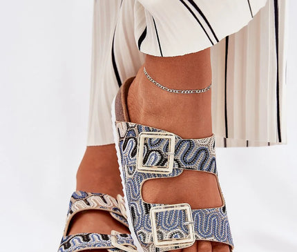 Sandales inspirées de l'artisanat brésilien aux motifs tissés évoquant les techniques traditionnelles, avec boucles métalliques dorées, semelle en liège et détail du pied mis en valeur, parfait pour un style estival et décontracté.
