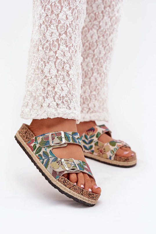 Sandales pour femmes de la marque Lee Cooper avec plateforme en liège tressé, deux brides réglables à motifs floraux colorés, boucles argentées à l'avant et semelle profilée pour un confort optimal, portées avec un pantalon blanc en dentelle, idéale pour les journées estivales.