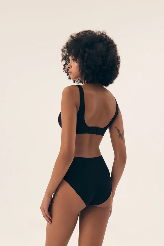 Sous-vêtement femme noir à taille haute inspiré de la mode brésilienne, avec un design minimaliste et épuré, reflétant l'élégance naturelle et la sensualité. Vue arrière sur un modèle mettant en valeur le confort et la liberté de mouvement, symbole des tendances populaires au Brésil.