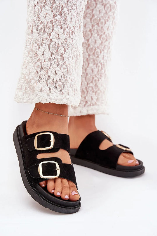 Sandales noires avec larges brides en suédine et boucles dorées, inspirées du style décontracté et élégant du Brésil. Idéales pour le confort quotidien et une allure chic, elles évoquent l'esprit des plages de Rio et des ruelles de Bahia.