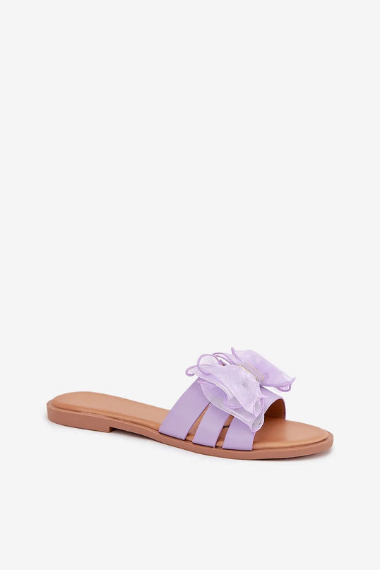 Sandales pour femmes en cuir écologique de couleur lavande avec un nœud en tulle décoratif, montées sur un talon plat de 1 cm, idéales pour les tenues estivales, assorties à des robes, jupes ou pantalons. Taille disponible entre 36 et 41.