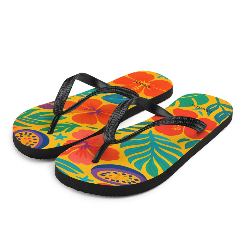 Tongs aux motifs tropicaux vibrants et colorés inspirés du Brésil, avec des imprimés de fleurs exotiques rouges, de feuillage vert et de fruits jaunes sur un fond jaune lumineux, reflétant l'esprit festif et ensoleillé des plages brésiliennes.
